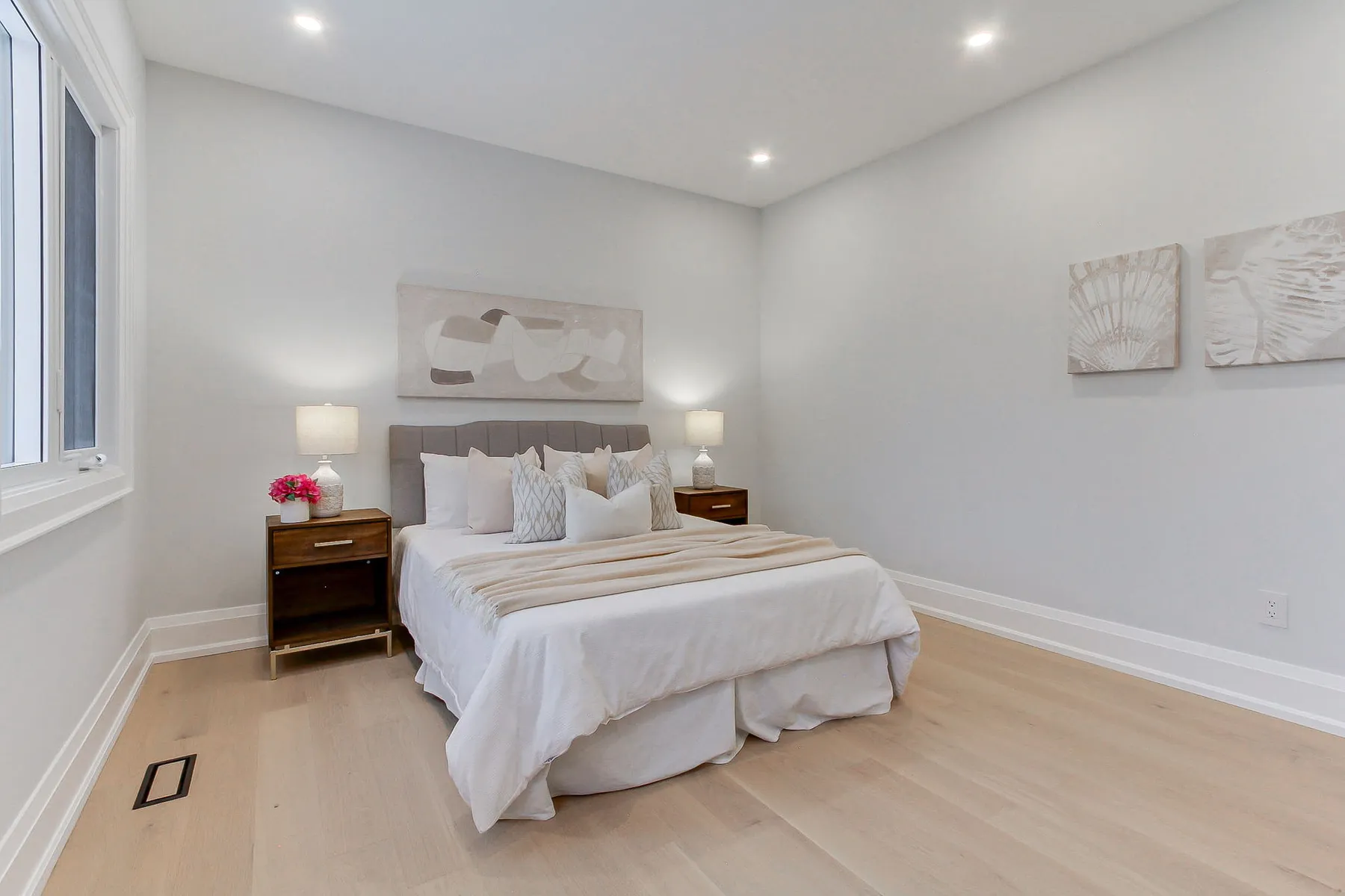 A secondary bedroom with an upholstered headboard, walnut nightstands and light oak floors