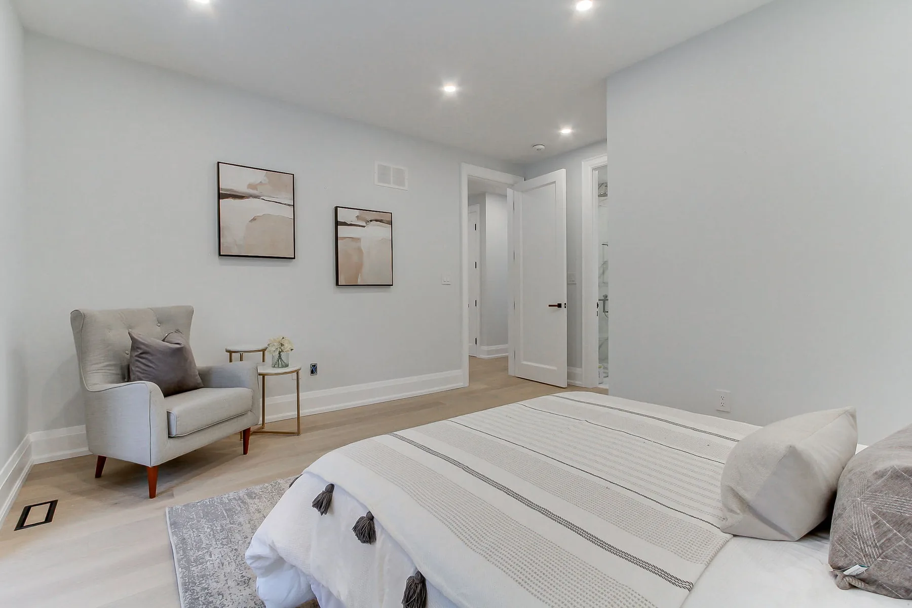 A further bedroom with a sitting chair by the window and a doorway through to its own bathroom