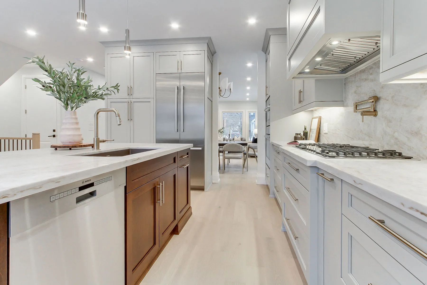 A finished custom kitchen viewed down the galley run, with full-height cabinetry and stone countertops