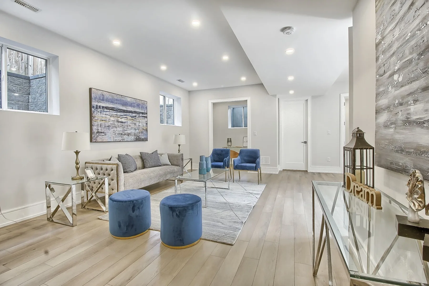 A front living room with a stacked-stone feature wall, pale floors and tall windows